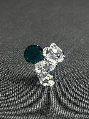 Crystal bear figurine with green gemstone on a gray background