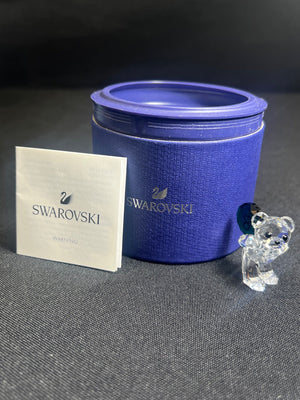 Swarovski branded blue container with a crystal bear figure and branded card on a gray background
