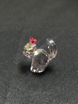 Crystal figurine of a rooster on a dark textured surface