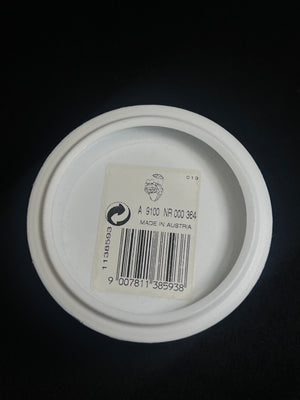 White container lid with a label and barcode on a black background