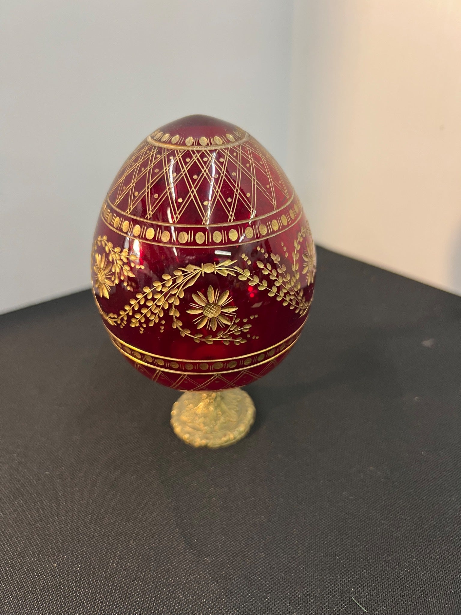 Decorative red egg with gold intricate patterns on a dark surface.