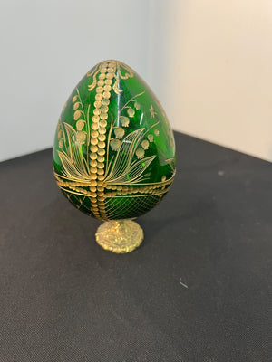 Decorative green egg with gold leaf patterns on a black surface
