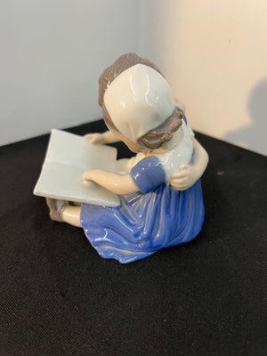 Figurine of a woman reading a book on a black surface