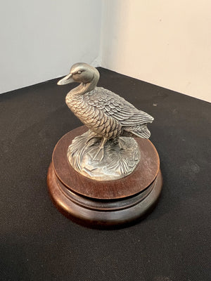 Decorative metal duck figure on a wooden base