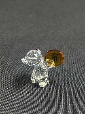 Small glass dog figurine with a brown base on a gray surface