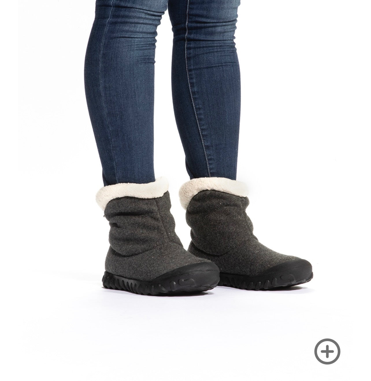 Gray slip-on boots with white fur lining worn with blue jeans on a white background