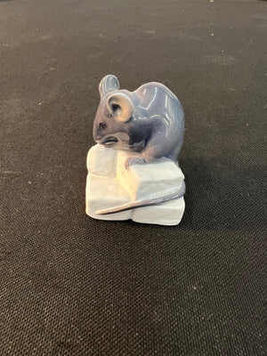 Small ceramic mouse figurine on a black background