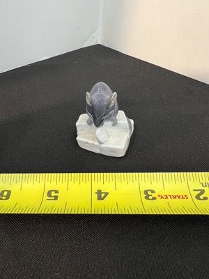 Small figurine of a mouse on a white base with a yellow measuring tape for scale.