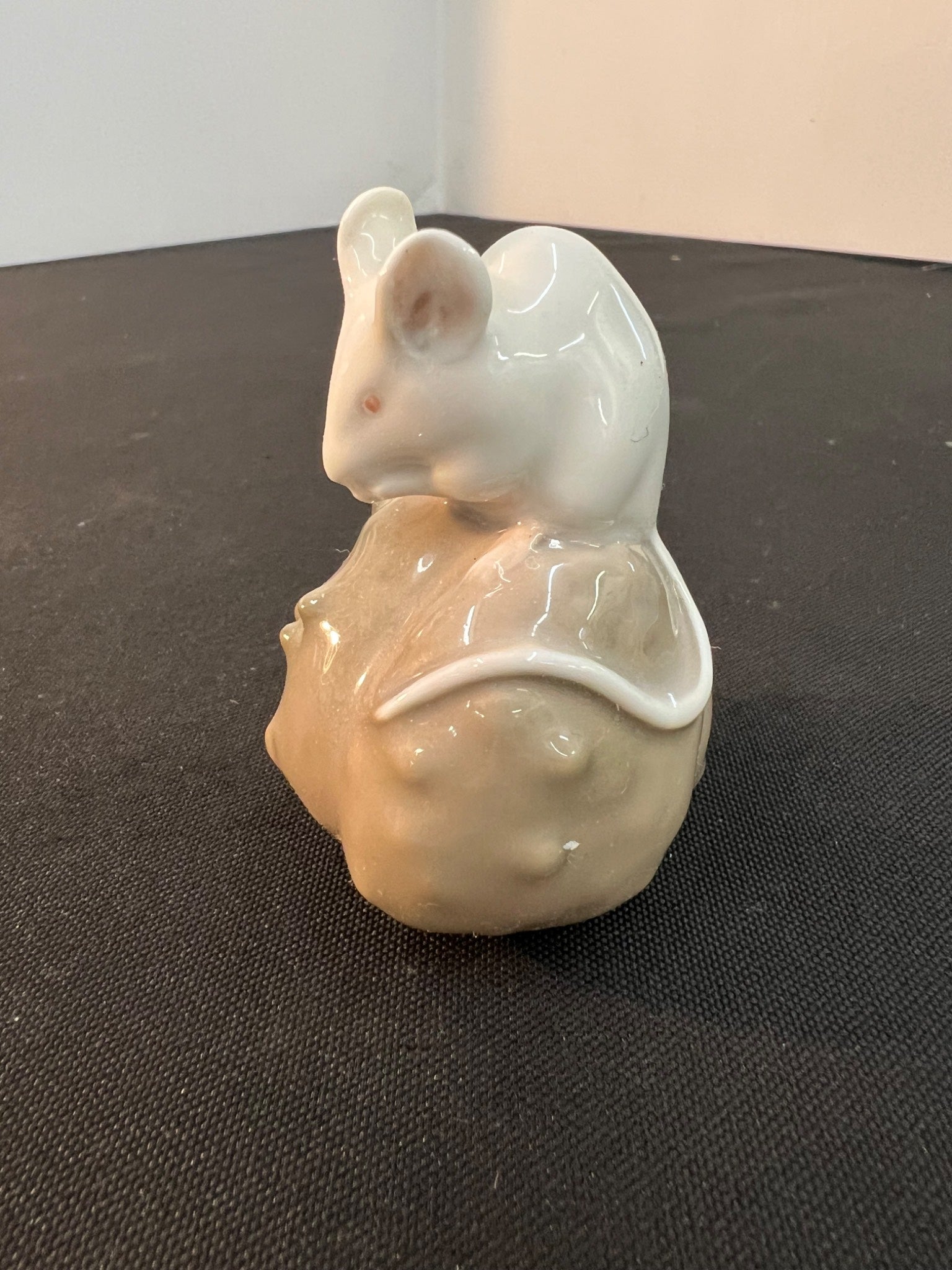 Ceramic mouse figurine with a shell on a dark surface