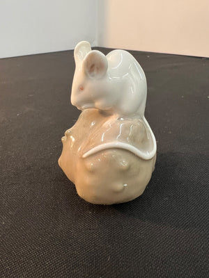 Ceramic mouse figurine with a shell on a dark surface