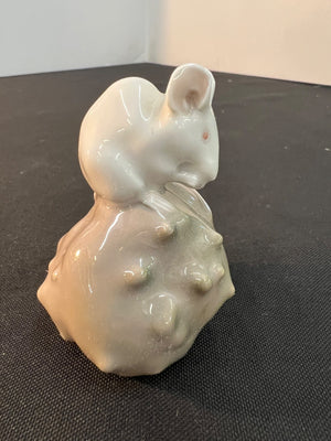 White ceramic mouse figurine on a textured black surface