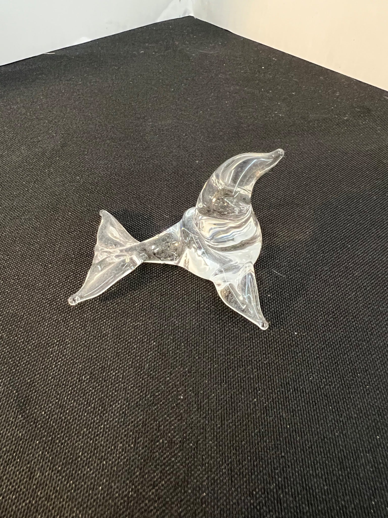 Clear glass dolphin figurine on a dark surface