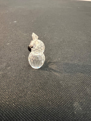 Clear glass snowman ornament on a dark textured surface