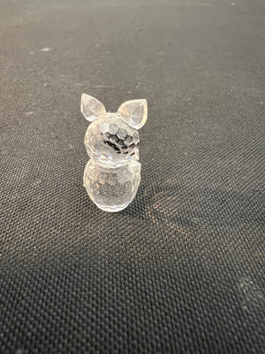 Clear plastic figurine of a dog on a textured black surface