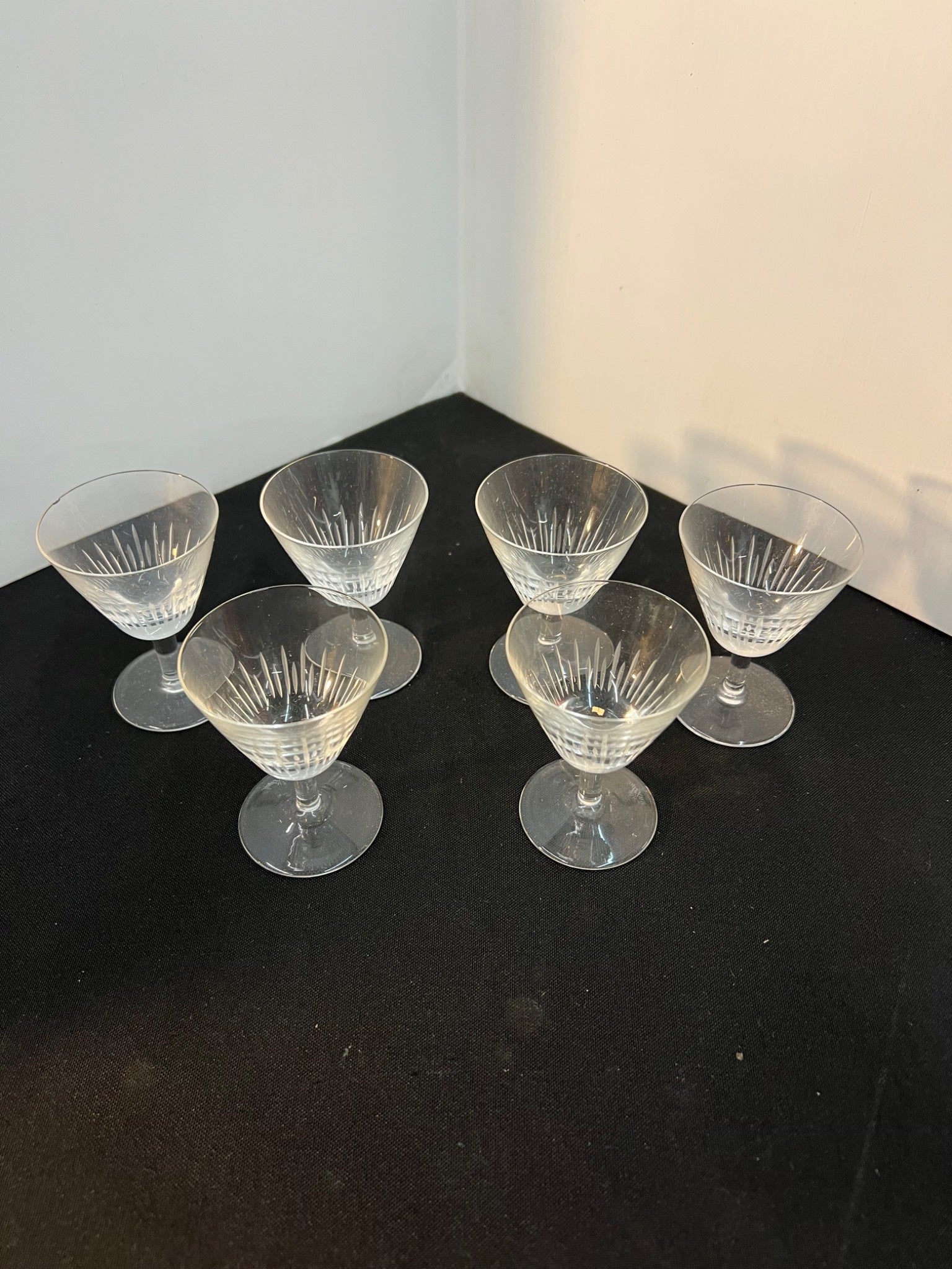 Set of six clear glass dessert cups on a dark surface with a white wall background