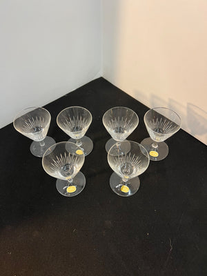 Set of six clear glass cocktail glasses on a black surface with a white background