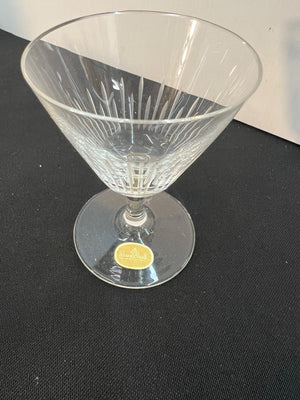 Clear glass cocktail glass with a gold label on a black background