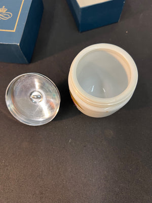 Small white jar with a silver lid on a dark surface