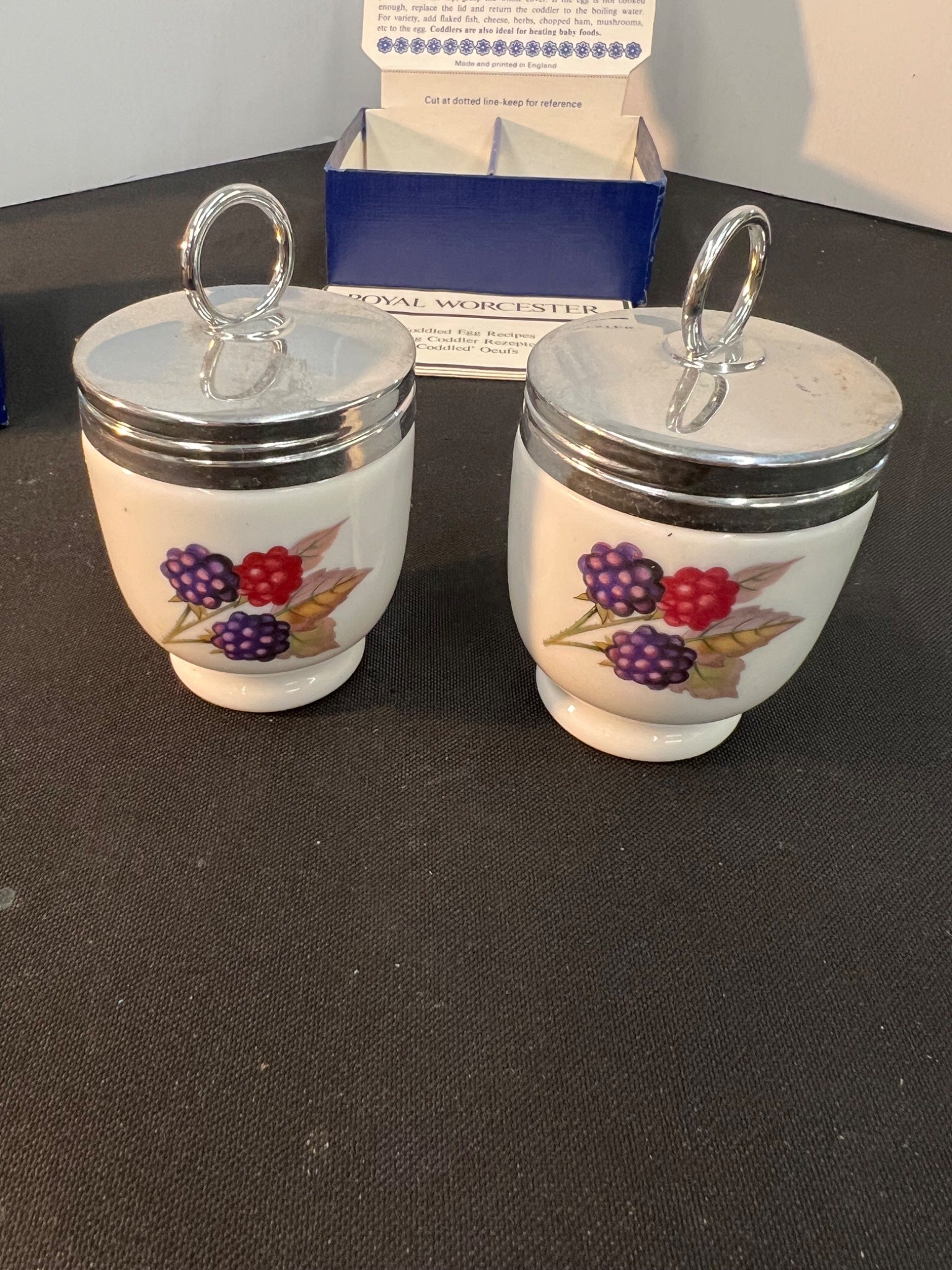 Two small ceramic jars with floral designs on a dark surface.