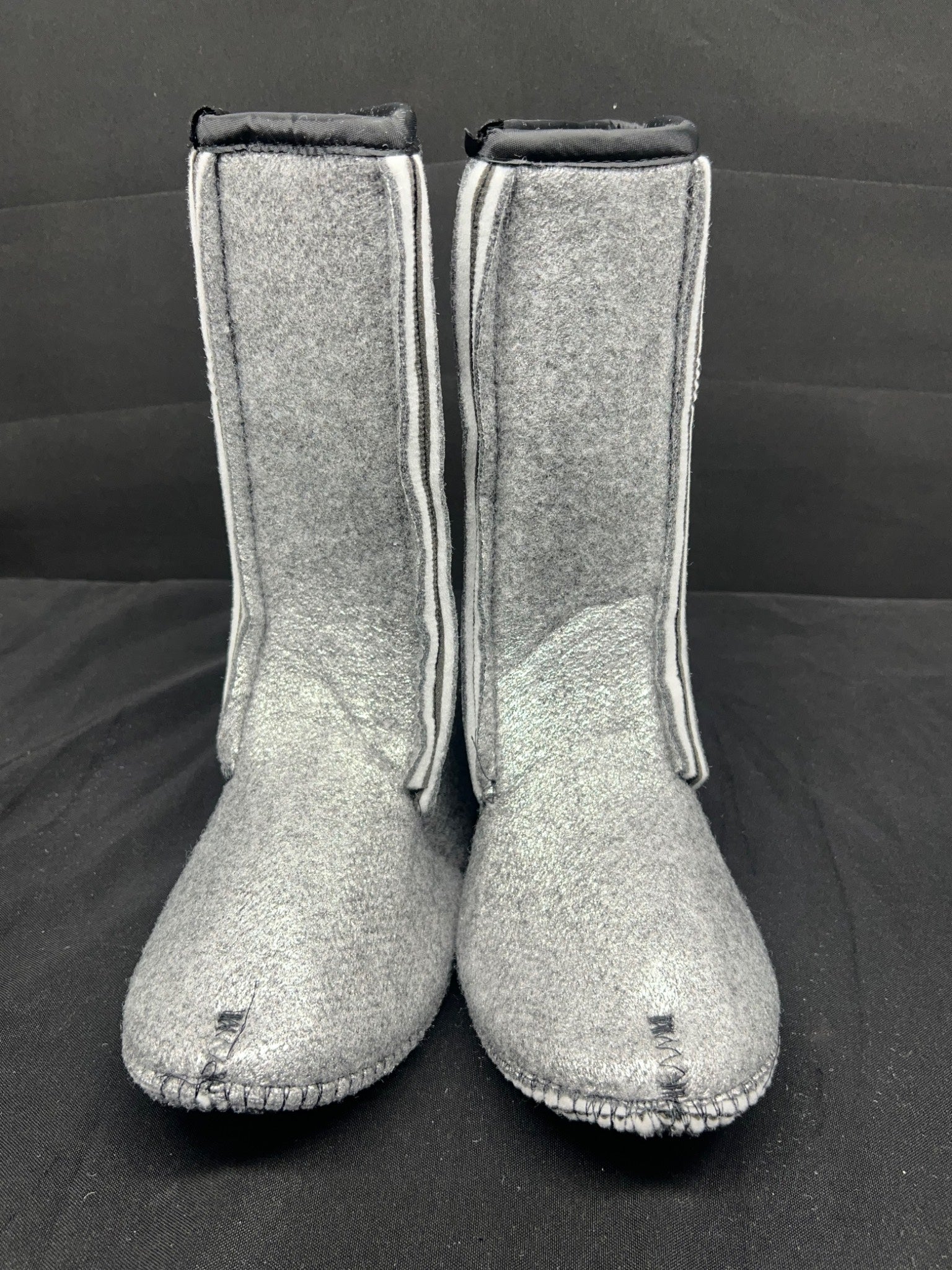 Pair of gray boots with white trim on a black background