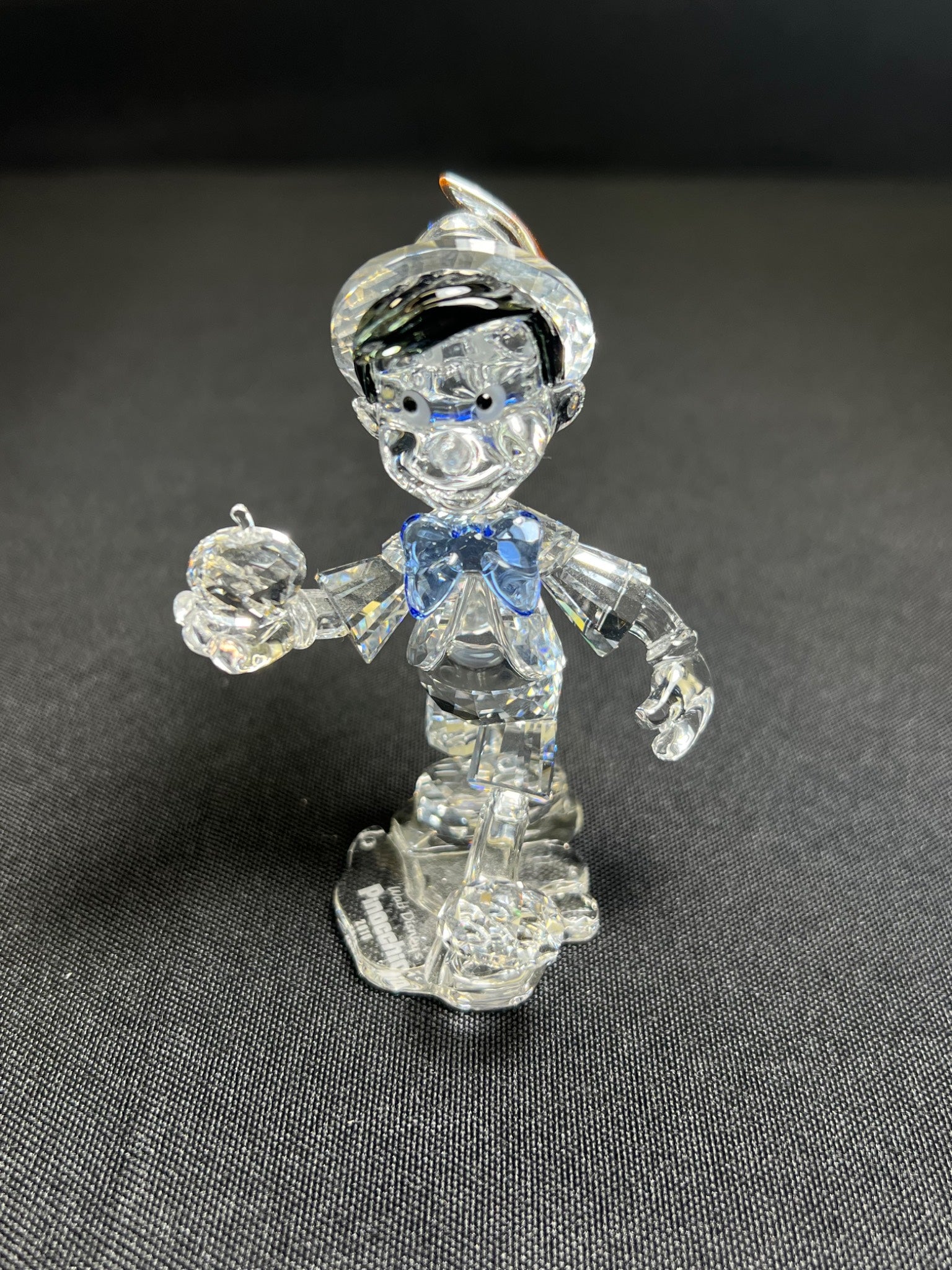 Clear glass figure of a character with a blue bow tie on a dark gray background