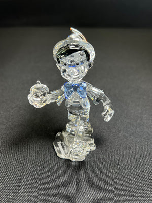Clear glass figure of a character with a blue bow tie on a dark gray background