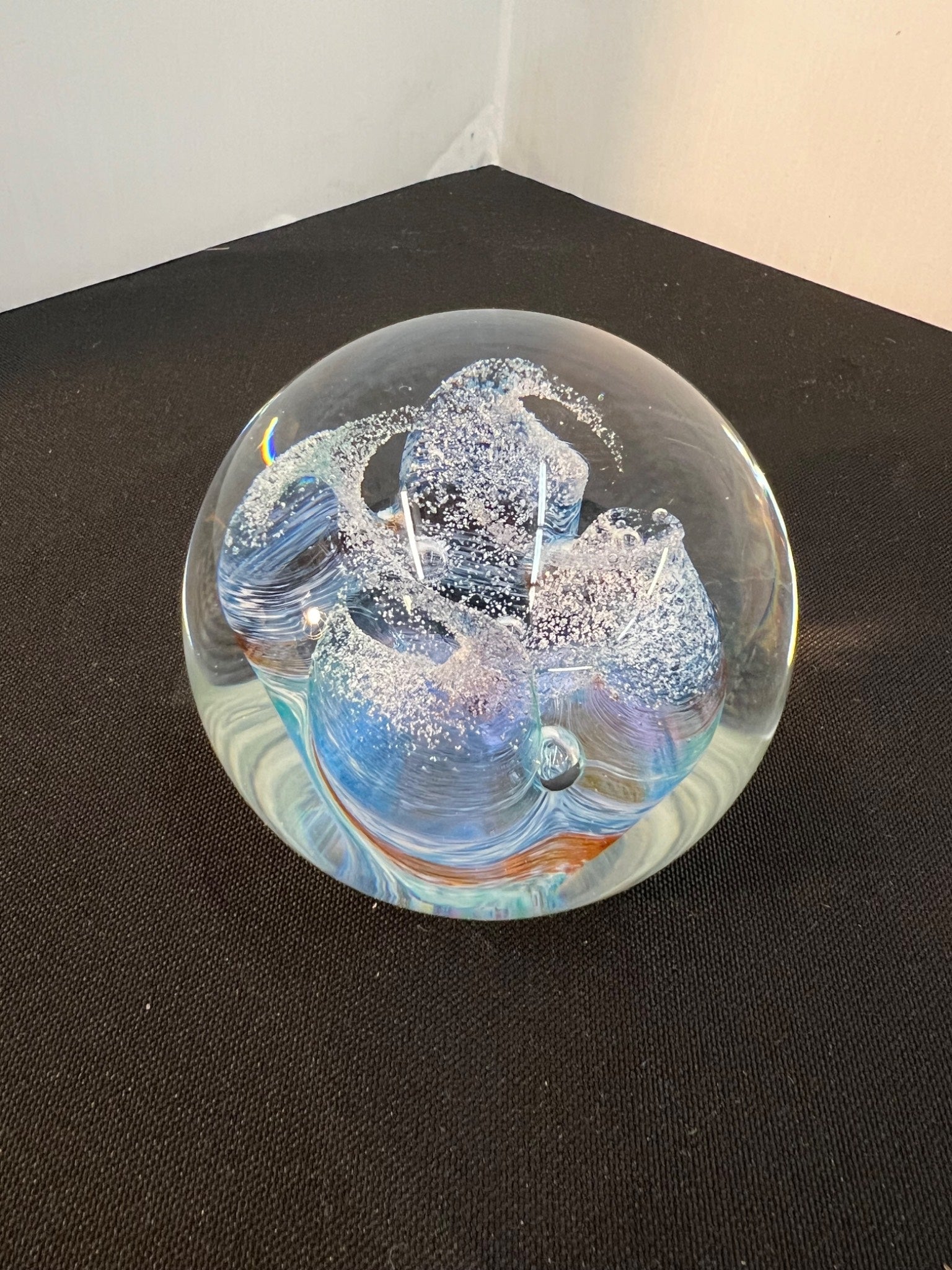 Glass paperweight with abstract design on a black surface