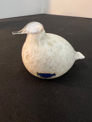 White ceramic duck figurine with a blue label on a black surface