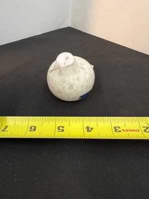 White spherical object on a black surface with a yellow measuring tape below.