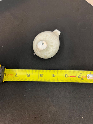 White spherical object on a black surface with a yellow measuring tape
