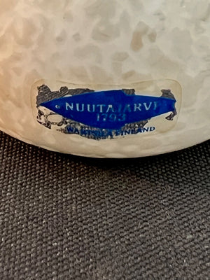 Close-up of a white ceramic item with a blue label on a textured surface