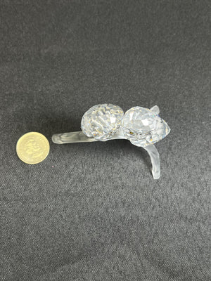 Crystal cat figurine next to a coin on a gray background