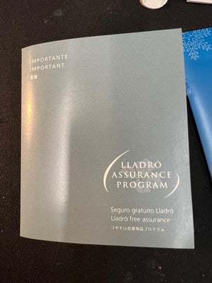 Lladró Assurance Program leaflet on a dark surface