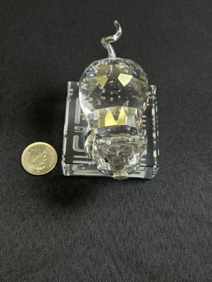 Small crystal object on a black background with a coin for scale