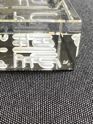 Clear plastic mold with letter 'F' on a textured black surface