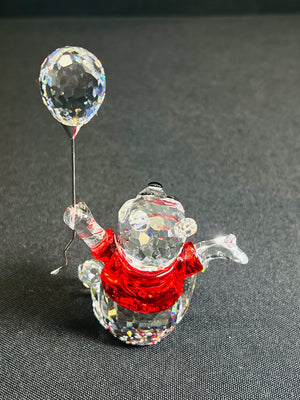 Crystal figure of a snowman with a balloon on a dark background