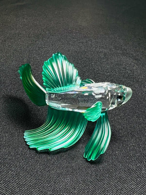 Glass fish figurine on a dark textured surface