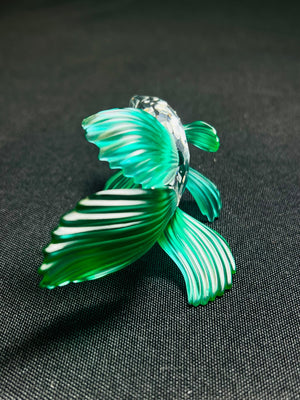 Green glass fish figure on a black fabric background