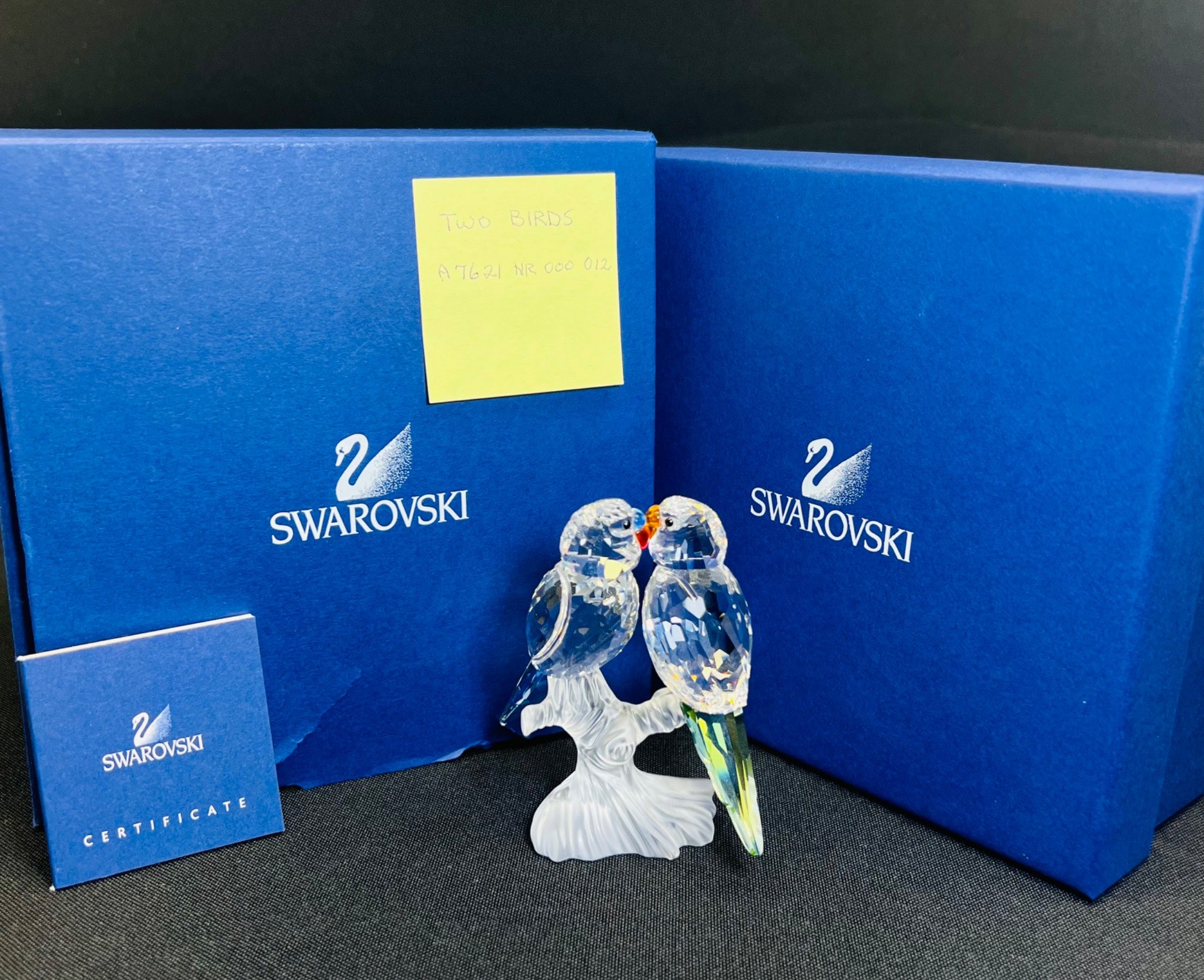 Swarovski crystal figurine of two birds on a branch with blue packaging and certificate.