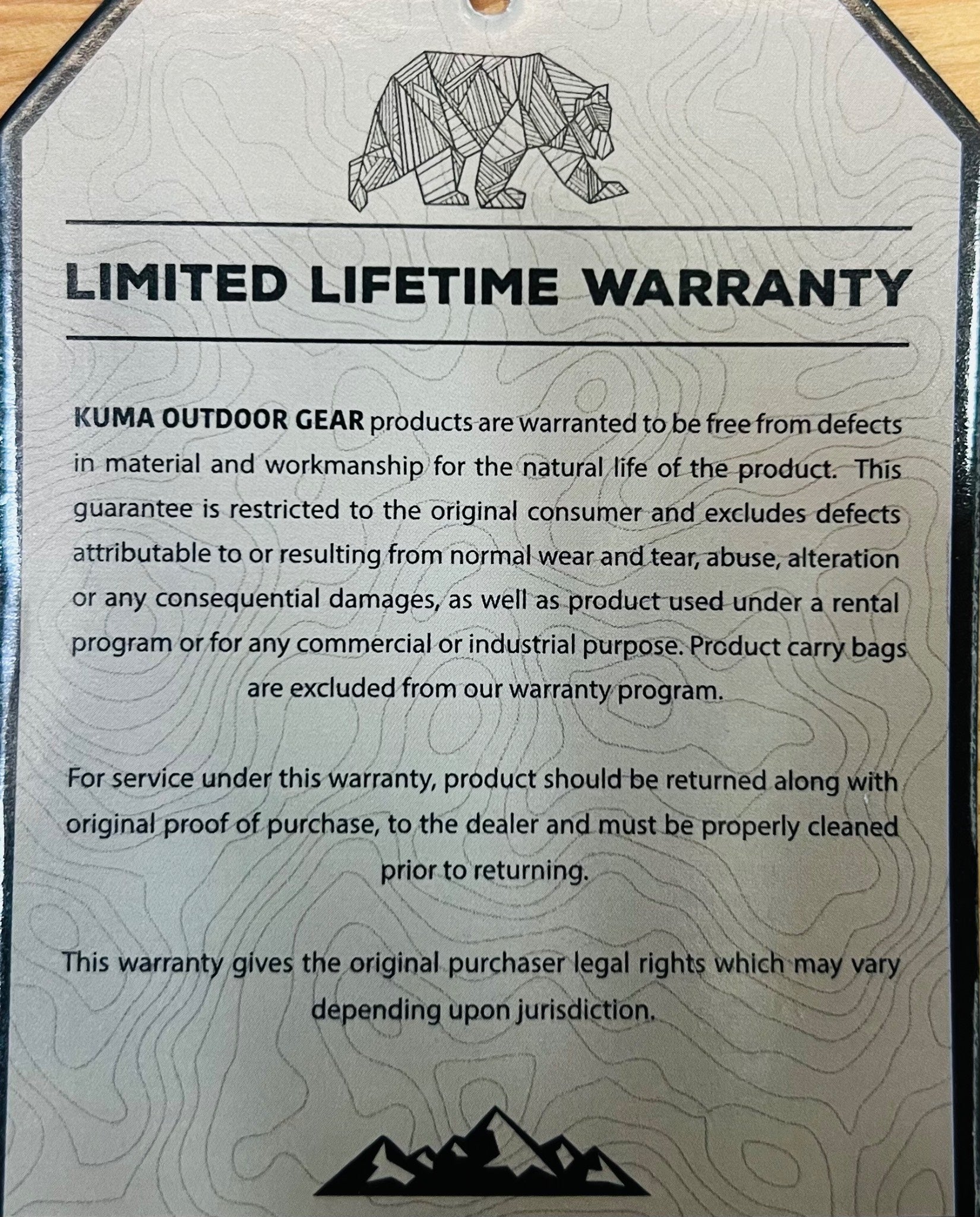 Kuma Outdoor Gear limited lifetime warranty card with text and mountain graphic.