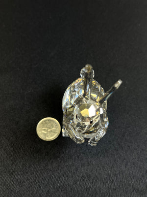 Crystal turtle figurine next to a coin on a black background