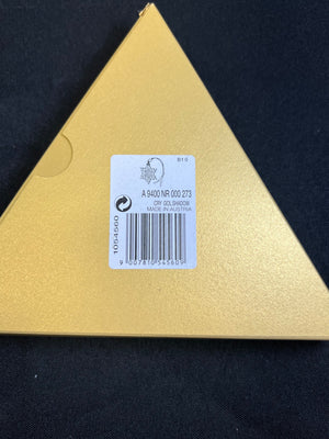 Triangular gold object with a label on a black background