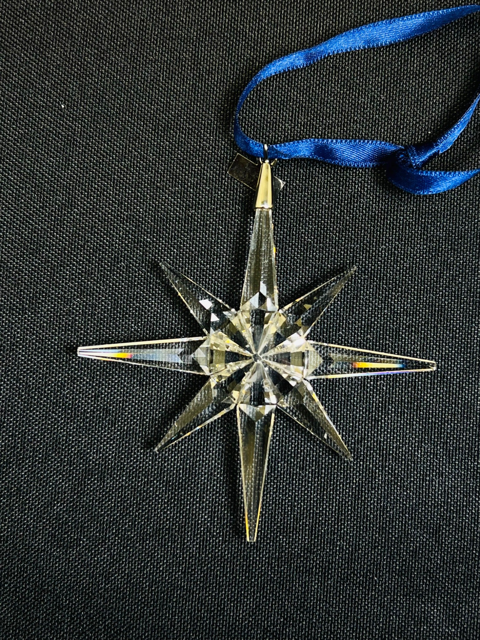 Crystal star ornament with blue ribbon on a black background