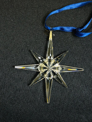 Crystal star ornament with blue ribbon on a black background