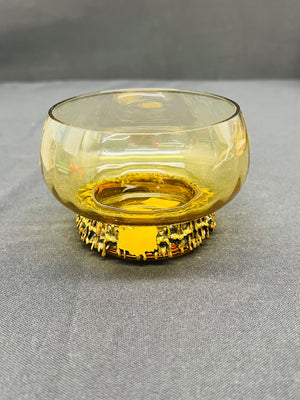 Amber glass bowl with decorative base on a gray surface