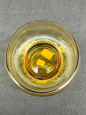 Clear glass bowl with amber liquid on a gray background