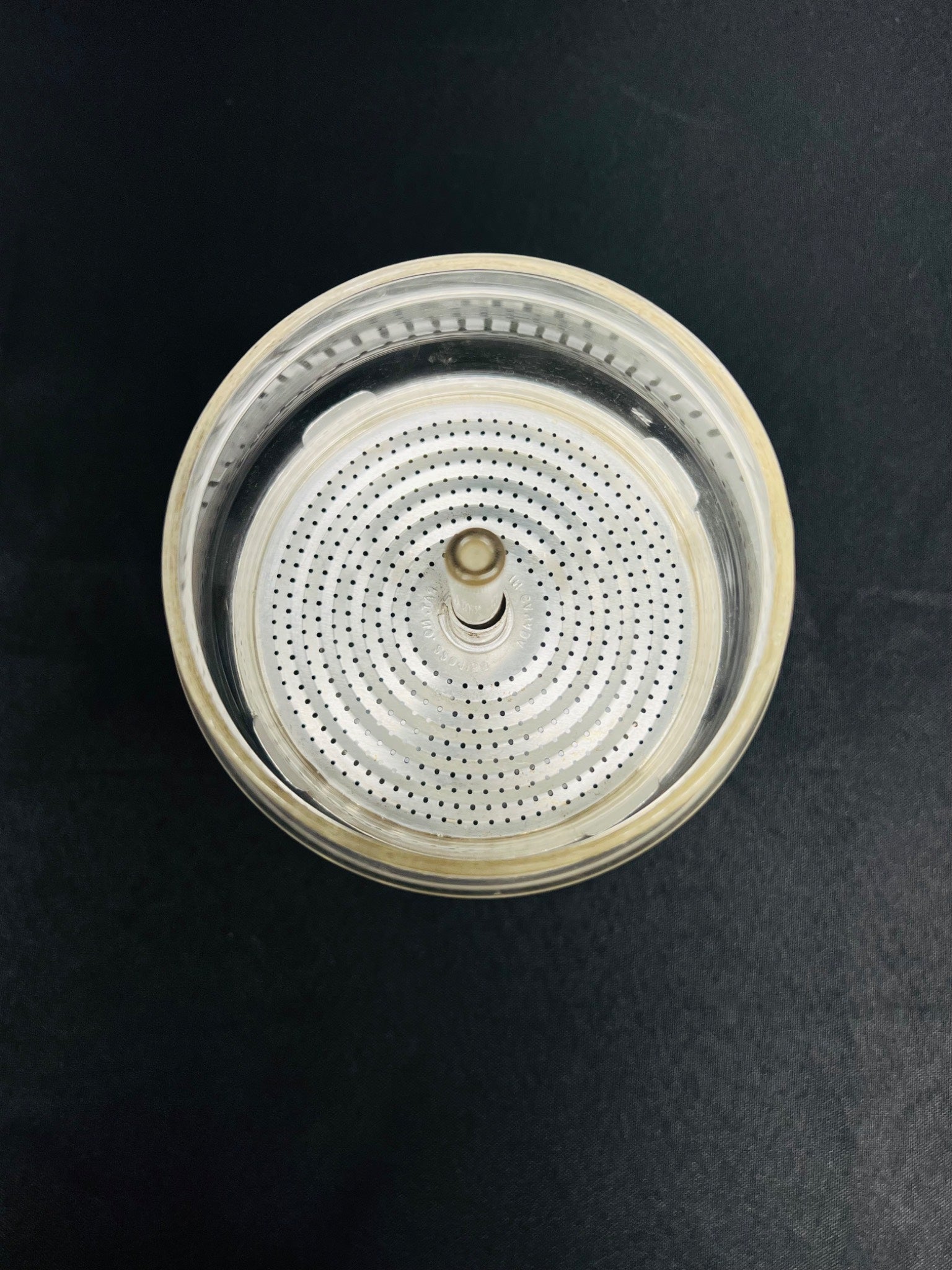 Round metallic object with a central shaft on a black background