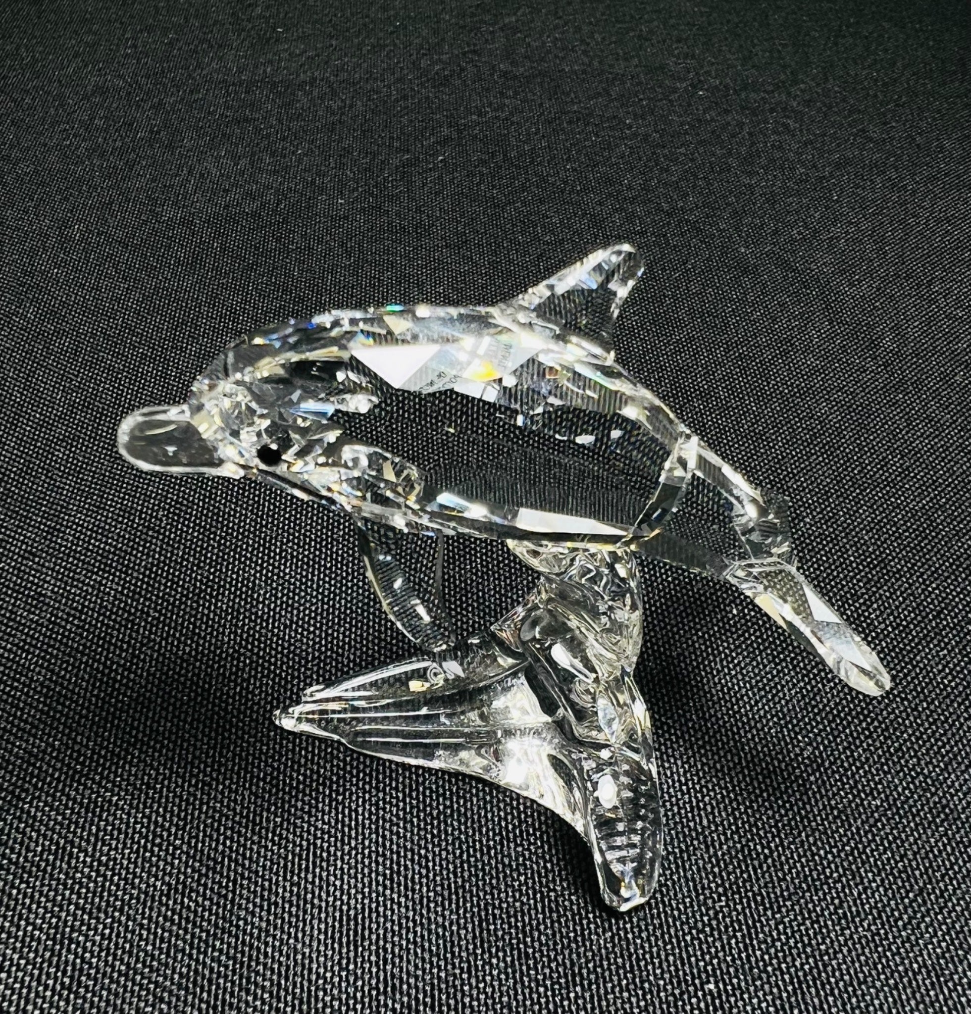 Clear glass dolphin figurine on a black background