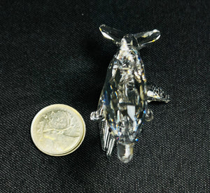 Crystal penguin figurine next to a coin on a black background