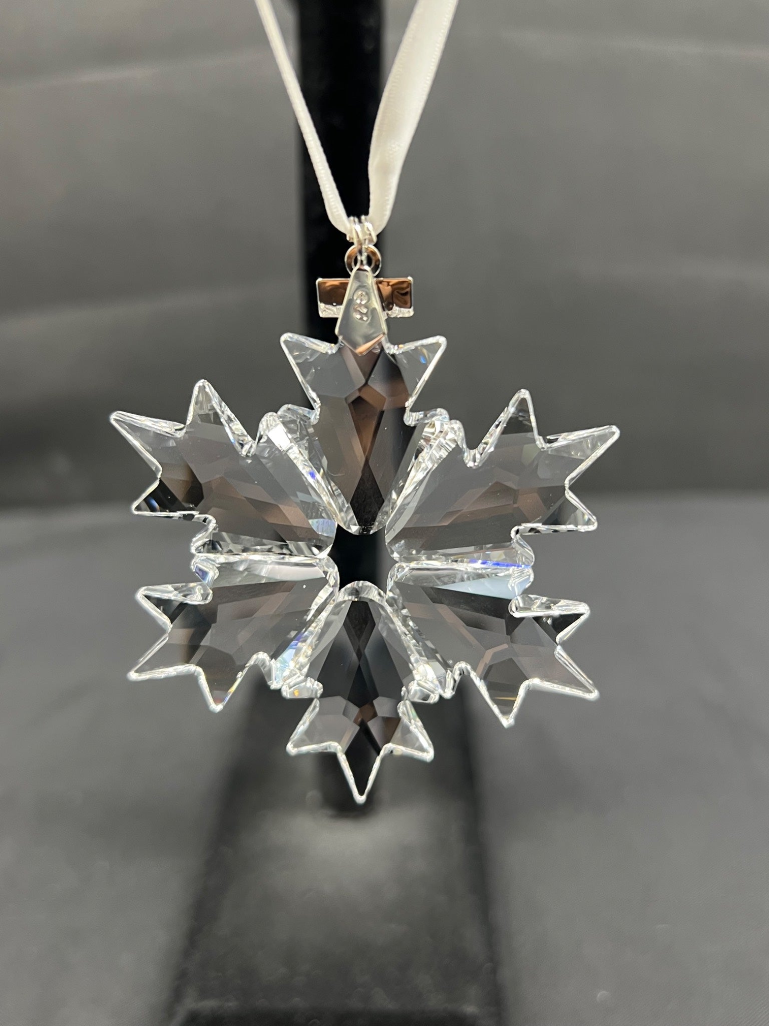 Clear snowflake-shaped ornament on a dark background